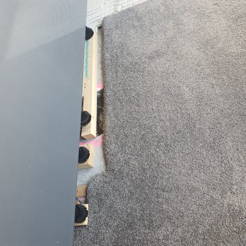 Grey carpet edge along a wall at a carpet repair job