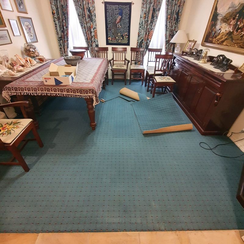 Teal living room carpet being restretched with furniture moved aside