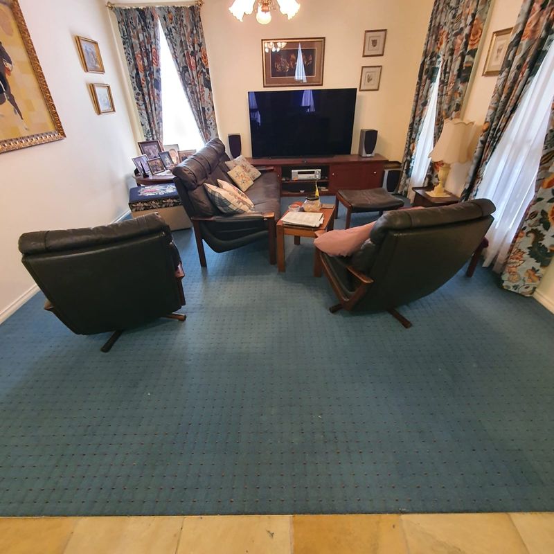 Lounge room with green carpet and recliner chairs at a carpet repair job